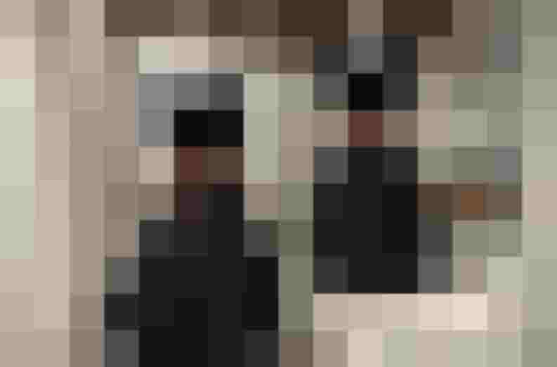 Zwei elegante, schwarze A-Linien Kleider mit braunen Gürtel in einem modernen Geschäft.
