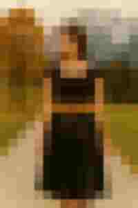 Frau in schwarzem Kleid mit braunem Gürtel auf Landweg