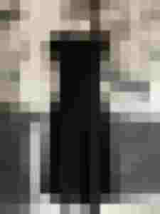Schwarzes klassisches Kleid auf Schneiderpuppe vor Wandbild